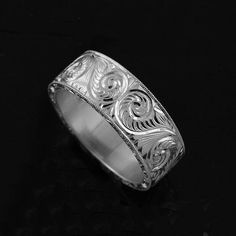 a silver ring with intricate designs on it's sides, against a black background