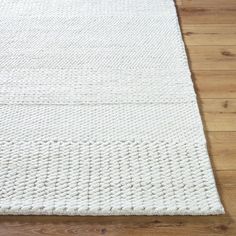 a white rug is laying on the floor in front of a wood flooring area