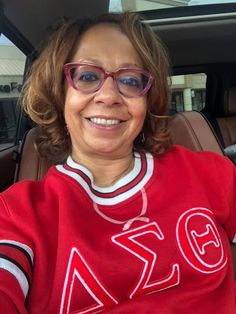 a woman wearing glasses sitting in the back seat of a car