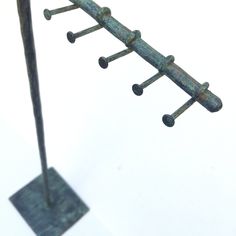 an iron sculpture with four rods attached to it's sides and one long pole sticking out from the ground