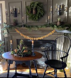 two chairs and a table in front of a fire place with wreaths on the mantle