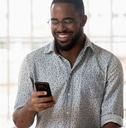 a man smiling while looking at his cell phone