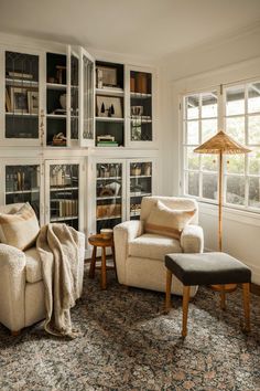 a living room filled with furniture and bookshelves next to a window on top of a rug