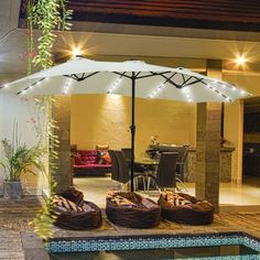 an open umbrella sitting on top of a patio next to a swimming pool