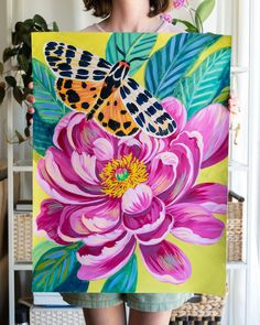 a woman holding up a painting with flowers