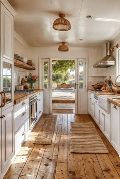 an open kitchen with white cabinets and wood flooring, along with a door leading to the outside