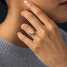 a close up of a person wearing a ring with a baguette on it