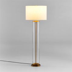 a floor lamp with a white shade on the base and a gold metal frame around it