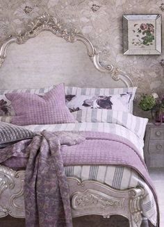 a bed with purple and white comforters in a bedroom next to a wallpapered wall