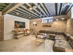 a living room filled with furniture next to a wall mounted flat screen tv on top of a brick wall