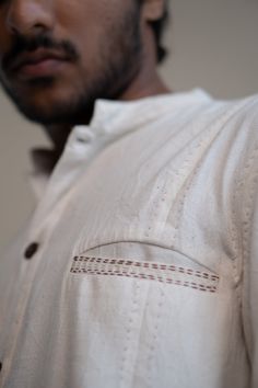 This Dawning Panelled Long Shirt comes in a calm and soothing color. This Kala Cotton shirt is undyed and unbleached. It has a band collar and full front panelling. This full-sleeve shirt comes with two patch pockets that are extensively adorned with stitches of Kantha, a form of Indian hand embroidery. *This item is a final sale and not eligible for returns or exchanges. *This item can take up to 14 business days to ship as it is made to order for you. Indian Hand Embroidery, Slow Clothing, 50th Clothing, Soothing Colors, Sewing Art, Suit Designs, Band Collar, Sustainable Clothing, Long Shirt