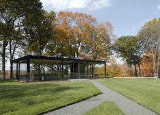 a glass pavilion sits in the middle of a grassy area surrounded by trees and grass