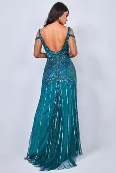 the back of a woman in a long dress with sequins on it, looking over her shoulder