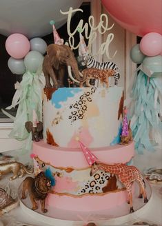 a three tiered cake decorated with animals and balloons