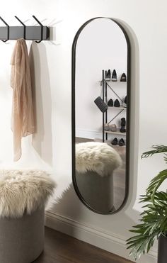 a large mirror sitting on top of a wall next to a potted plant and shoe rack