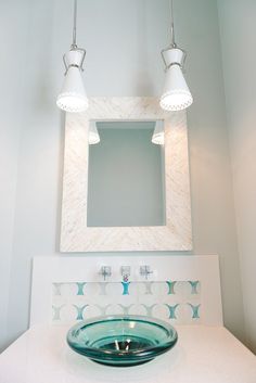 a bathroom sink with two lights above it and a mirror on the wall behind it