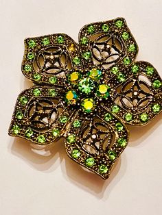 Vintage austria style  green and aurora borealis glass rhinestones set in a raised filagree  relief multi stone  detail flower setting. It is measuring  2 in diameter. Please be sure to view all of my photos. one tiny green stone missing otherwise no issues. Green Jeweled Brooch For Gift, Green Jeweled Brooches As Gift, Green Rhinestone Wedding Brooch, Green Rhinestone Wedding Brooches, Elegant Green Rhinestone Brooches, Vintage Green Rhinestone Brooches, Green Vintage Rhinestone Brooches, Ornate Green Brooches For Wedding, Vintage Green Rhinestone Brooch