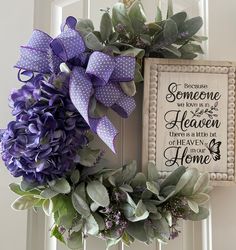 two wreaths with purple flowers are hanging on the front door and one has a sign that says someone is in heaven