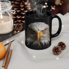 a coffee mug with an eagle's head on it next to pine cones and candles