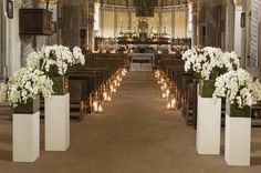 the interior of a church with candles and flowers in vases on the pews