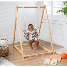 a baby swinging on a wooden swing set