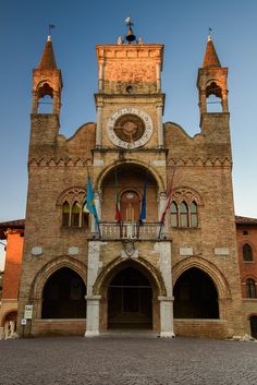 an old brick building with two towers and a clock on it's front entrance