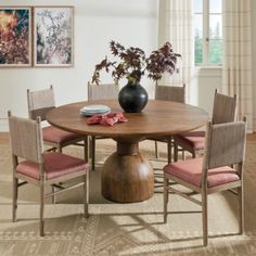 a round wooden table with four chairs around it and a vase on top of the table