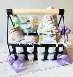 a basket filled with items sitting on top of a white table next to a purple ribbon