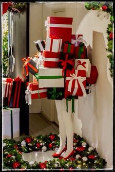 a mannequin dressed up in christmas presents and holding a large stack of gifts