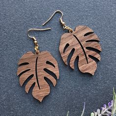 two wooden earrings with monster leaves on them