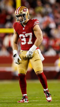 a football player standing on the field with his hands in his pockets and wearing a helmet