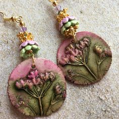 two pink and green earrings with flowers on them