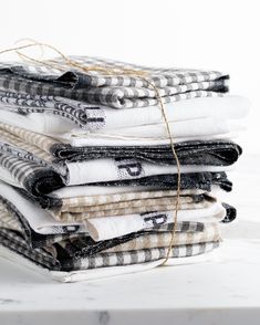 a stack of folded towels sitting on top of a white counter next to a black and white checkered cloth