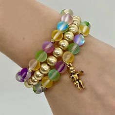 Bring on the Mardi Gras season with this super fun stack! This Hand Beaded set of 3 stack bracelets includes:- 8mm brushed gold round bracelet- Mardi Gras mix Aura Quartz with gold accents- Mardi Gras mix Aura Quarts with gold accents and King Cake baby charm. Bracelets are “one size fits most” and are designed to fit wrists up to 7.0”. Custom sizes available upon request. Please email designsby.kb@yahoo.com once your oder is placed. *Bracelets usually ship within 3-5 business days. Gold Jewelry With Colorful Beads For Layering, Party Gold Bracelet With 8mm Beads, Gold Bracelets With 8mm Beads For Party, Gold Stretch Bracelet With 8mm Beads For Party, Gold Charm Bracelet With Round Beads For Party, Gold Stacked Bracelets With Round Beads, Gold Spiritual Bracelets For Parties, Gold Bracelets With Colorful Beads For Party, Adjustable Gold Stacked Beaded Bracelets