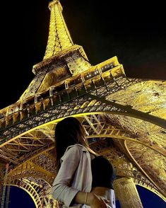 a woman standing in front of the eiffel tower at night with her hand on her hip