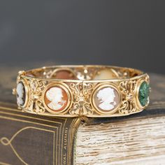 This piece of jewelry comes with it a deep sense of nostalgia! I adore the colors on the different cameos - such a sweet way to add color to one's wrist. But the bets part is the piece's original receipt, dated 1976 from Italy, and its original box. Beautiful an romantic workmanship as only the Italians can! Just beautiful on the wrist. 14kt yellow gold Will fit up to a 7.5" wrist. Please see qualitative report for more information. Luxury Vintage Bracelets For Anniversary, Vintage Yellow Gold Cabochon Bracelets, Antique Cabochon Bracelets For Wedding, Wedding Bangle Bracelet With Cabochon, Intaglio Bangle Jewelry As A Gift, Formal Intaglio Bangle Jewelry, Vintage Intaglio Bracelets For Formal Occasions, Vintage Cabochon Bracelets For Formal Occasions, Vintage Gemstone Bangle For Formal Occasions