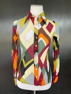 1970s Wayne Rogers blouse. Multicolor almost sheer crepe texture nylon. Nine button front. Two button cuffs. Size 7/8 Measurements  32" bust 24" midriff  30" hem 23" length 22" sleeves 13" shoulders There is a decent amount of stretch to this fabric. Lovely blouse shows beautifully with no wear.  Deadstock item with Bonwit Teller hangtag still attached. Multicolor Retro Print Button-up Top, Fitted Multicolor Fall Shirt, Retro Tops With Colorful Pattern For Fall, Retro Colorful Patterned Tops For Fall, Colorful Patterned Fitted Long Sleeve Tops, Fitted Long Sleeve Multicolor Print Blouse, Fitted Multicolor Print Long Sleeve Blouse, Multicolor Collared Blouse With Buttons, Fitted Multicolor Print Blouse For Fall