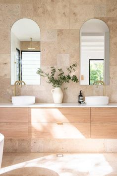 A bathroom features a double vanity with brushed brass tapware and floor to ceiling travertine stone tiles. Mediterranean Bathroom, Ideas Baños, Coastal Bathrooms, Bathroom Design Inspiration, Bathroom Renos, House Bathroom