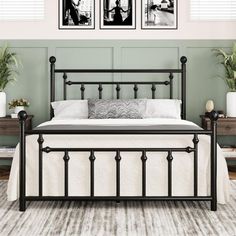 a black metal bed frame with two pictures on the wall above it