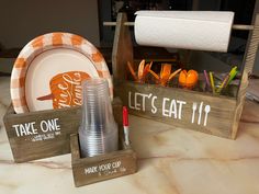 there are plates, cups and napkins in wooden holders on the kitchen countertop