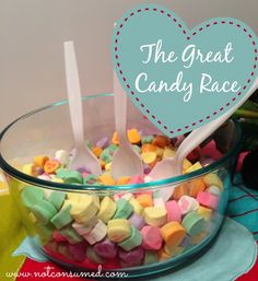 a bowl filled with marshmallows next to a heart shaped sign that says the great candy race