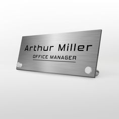 a metal sign with the name of an office manager on it's back side