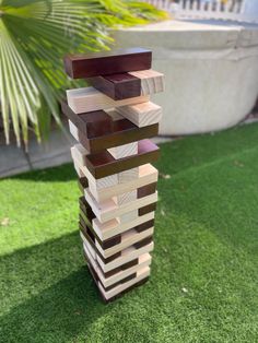 a stack of wooden blocks sitting on top of a lush green field next to a potted plant