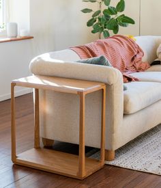 a white couch sitting on top of a hard wood floor next to a wooden table