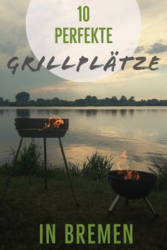 two bbq grills sitting next to each other on top of grass near water