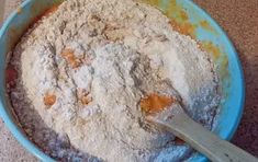 a blue bowl filled with flour next to a wooden spoon