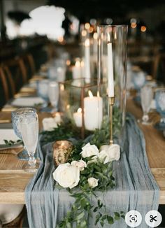 the table is set with candles, flowers and greenery for an elegant dinner party