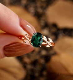 a woman's hand holding an emerald ring