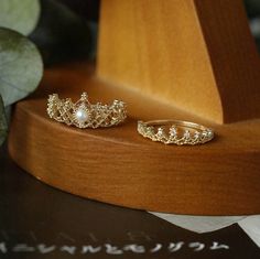 two gold rings sitting on top of a wooden stand