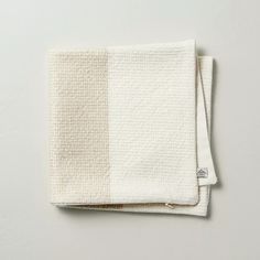 two towels folded on top of each other in white and beige colors, with the same color